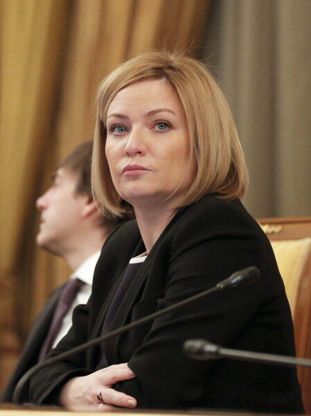 Женщина на деловой встрече, смотрит в сторону, формальная обстановка, микрофоны.