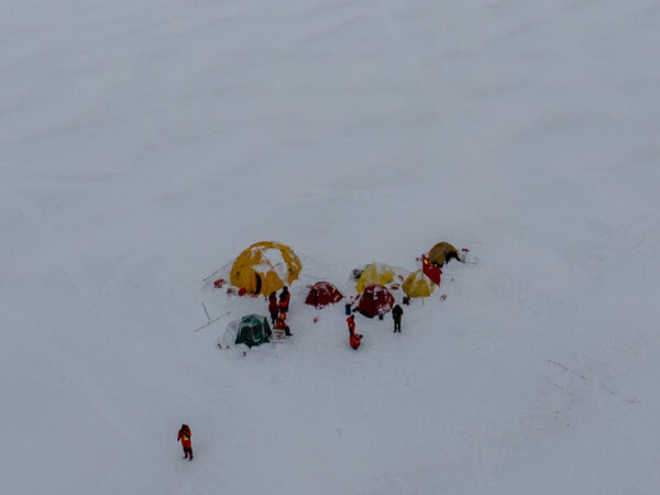 Палаточный лагерь на снегу, люди в зимней одежде, полярная экспедиция.