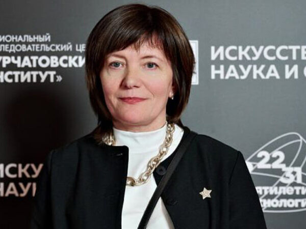 Наш человек в академии 2 Женщина на фоне постера научного мероприятия в Курчатовском институте.