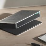 Современный проектор на столе рядом с блокнотом и ручкой.