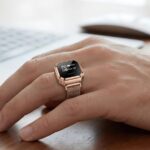 Смарт-кольцо на руке с экраном, рядом ноутбук, современная технология.