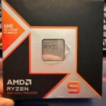 Упаковка процессора AMD Ryzen 9 с технологией 3D V-Cache на фоне клавиатуры.