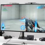 Компьютерный монитор с видеоигрой на столе, клавиатура и контроллер рядом.