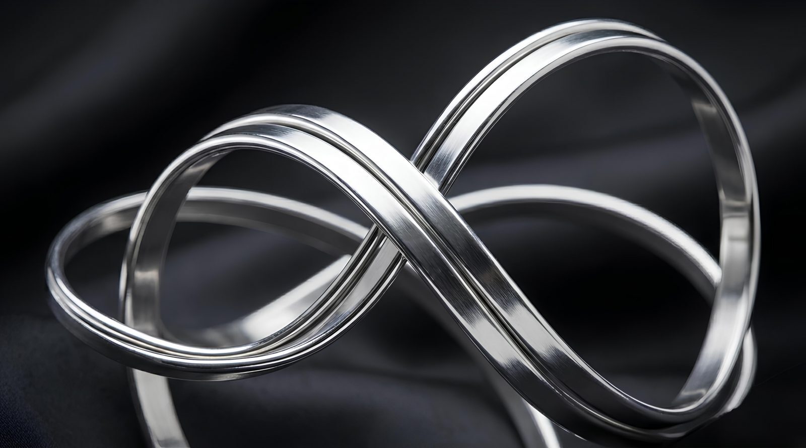 Серебряная лента в форме бесконечности на темном фоне.