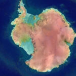 Спутниковый снимок Антарктиды, окутанной льдом, на фоне синего океана.