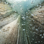 Подводный вид из ущелья с пузырьками воздуха и слоистыми камнями.