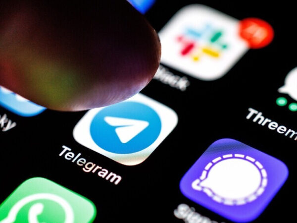 Палец нажимает на иконку приложения Telegram на экране смартфона.