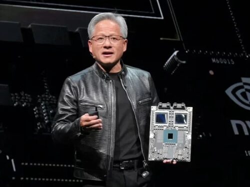 Человек в кожаной куртке держит чип для презентации технологии на сцене.