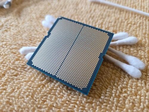 Процессор на фоне ватных палочек, лежащий на текстурированной поверхности.