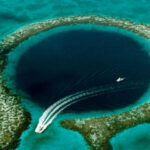 Яхта у Голубой дыры в Белизе, окруженной бирюзовой водой.