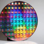 Кремниевый полупроводниковый чип с ярким голографическим узором на сером фоне.