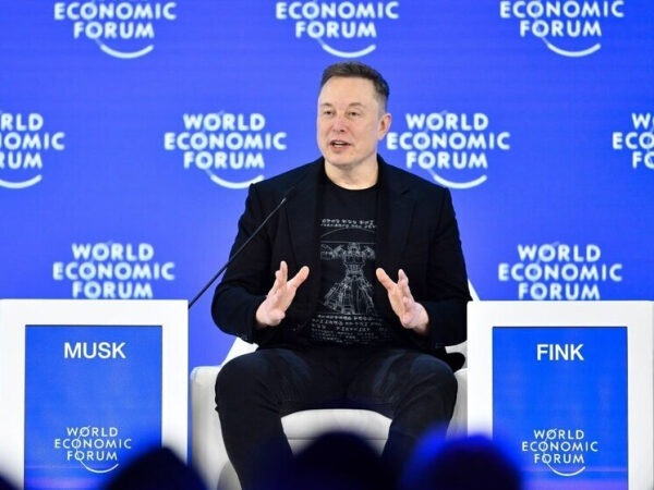 Участник Всемирного экономического форума на фоне синего баннера с логотипом форума.