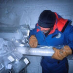 Человек изучает ледяной керн в антарктической лаборатории.