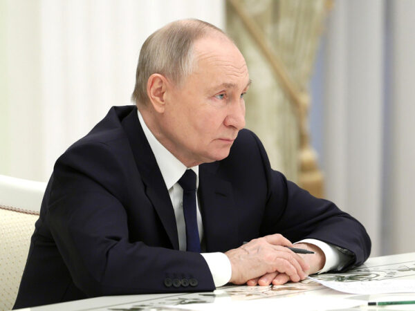 Мужчина в костюме сидит за столом с бумагами, внутренний интерьер офиса.