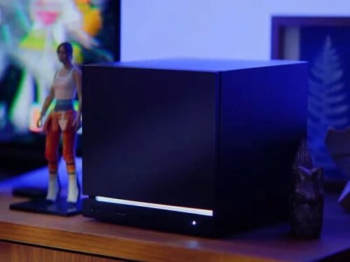 Черная квадратная колонка на тумбе дома, рядом фигурка, синий фон.