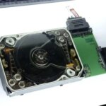 Старый жёсткий диск с прозрачной крышкой, разобранный для показа внутренней структуры.