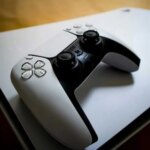 Игровая консоль и контроллер на деревянной поверхности.