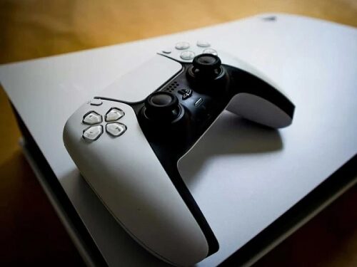 Игровая консоль и контроллер на деревянной поверхности.