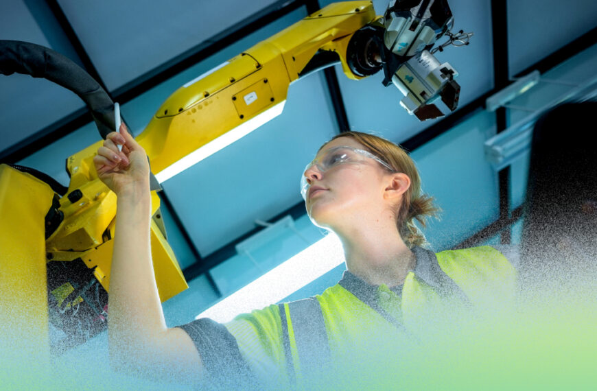 Человек работает с промышленным роботом на производстве, проверяя оборудование.