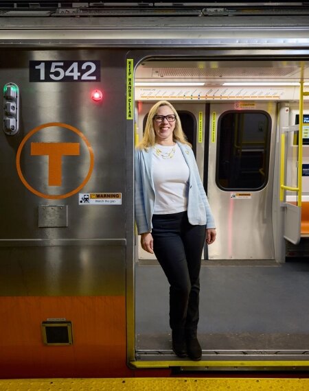 Женщина в деловом костюме стоит у двери поезда на станции метро.