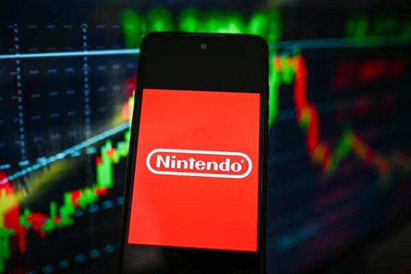 Смартфон с логотипом Nintendo на фоне финансовых графиков.
