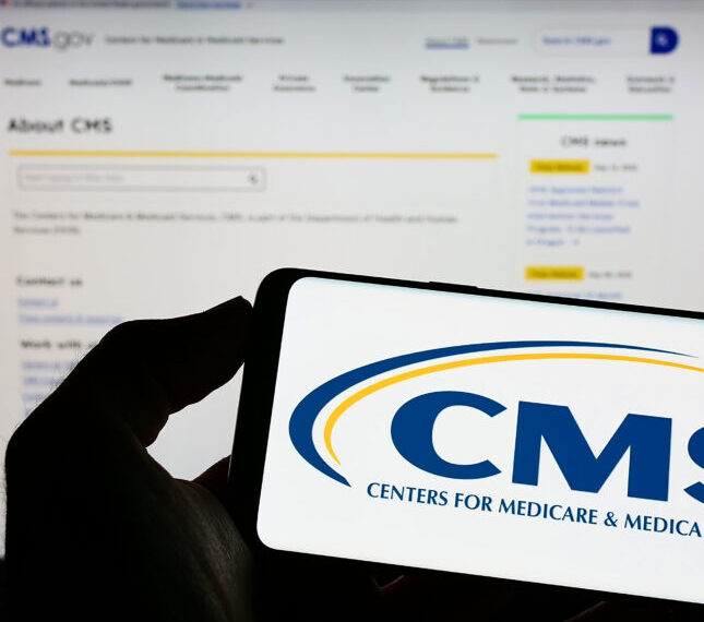 Логотип CMS на экране смартфона, сайт в фоновом режиме.