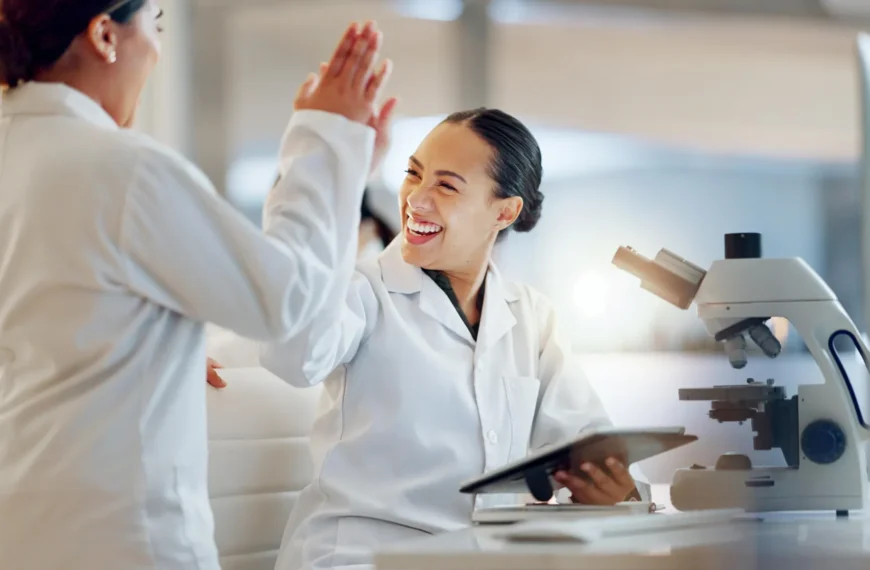 Два ученых в лаборатории обсуждают результаты перед микроскопом.