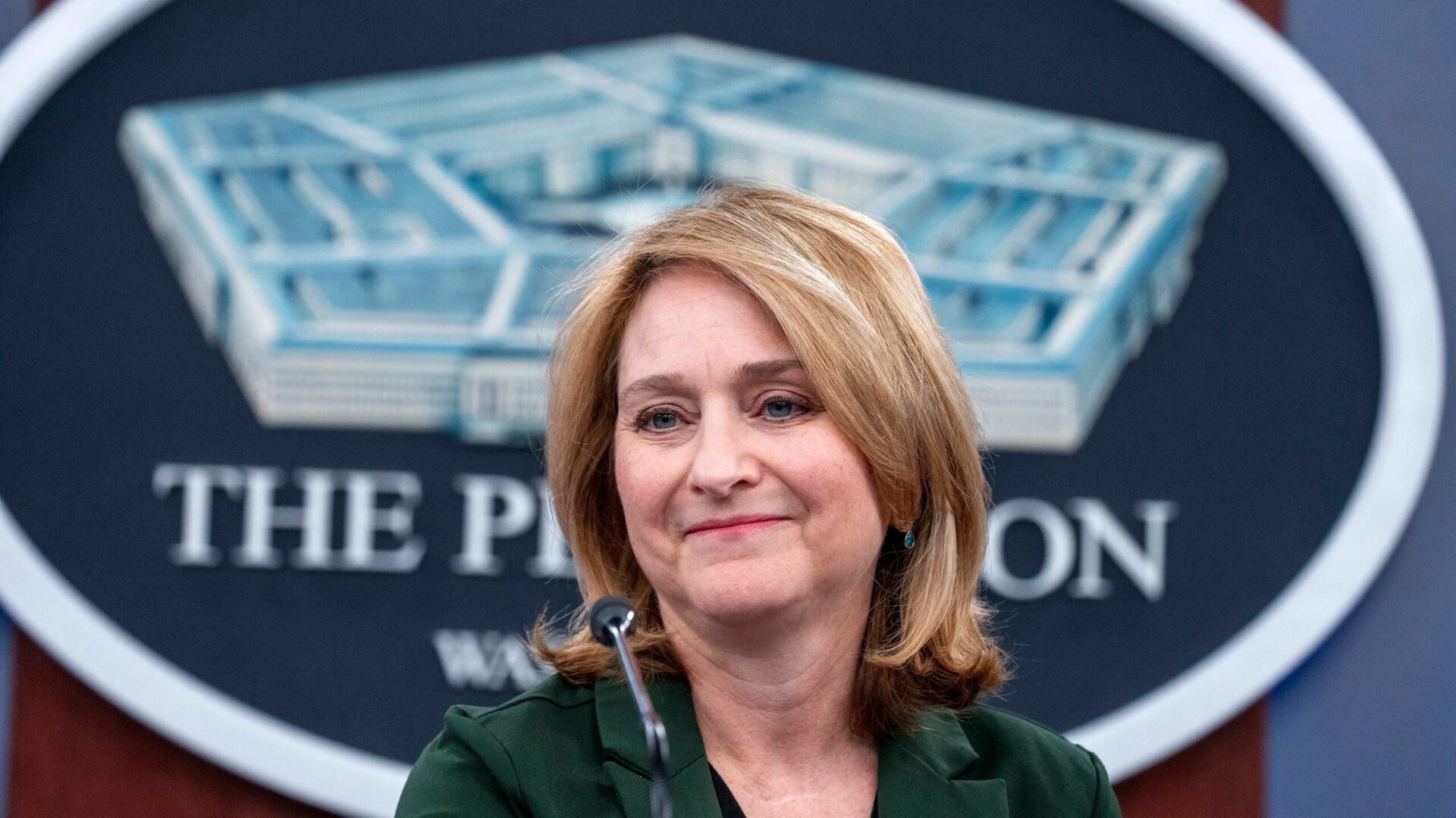 Женщина на пресс-конференции у микрофона на фоне вывески Пентагона.