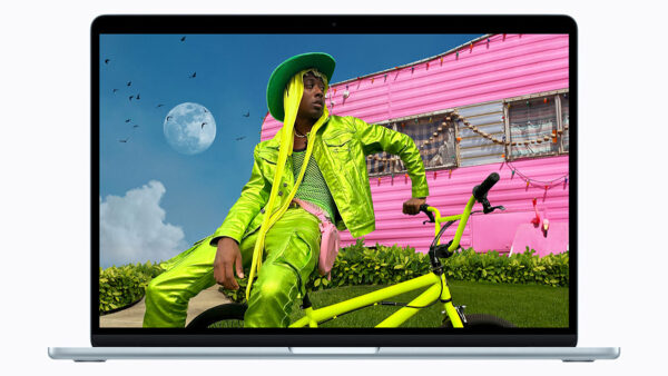 Человек в зеленом костюме на велосипеде перед розовым домом.