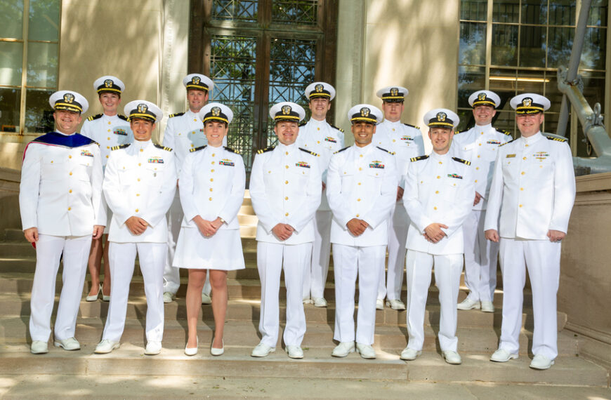 Группа военнослужащих в белой форме на ступенях перед зданием.