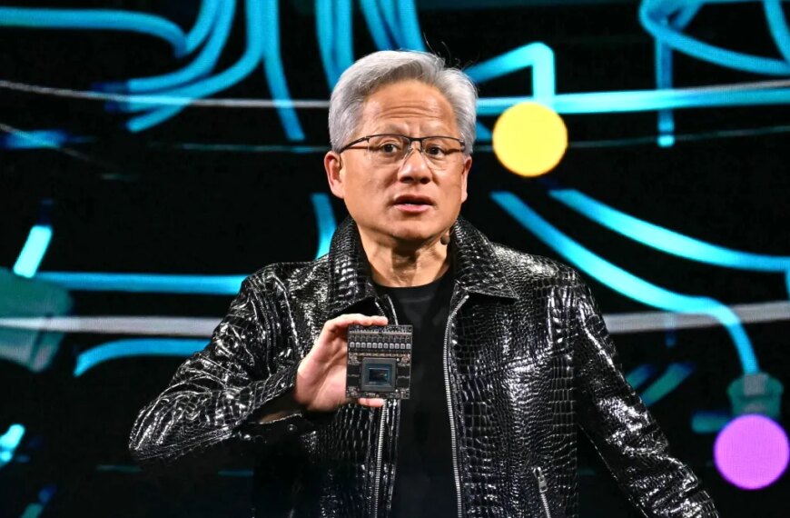 Человек в кожаной куртке демонстрирует процессор на футуристическом фоне.