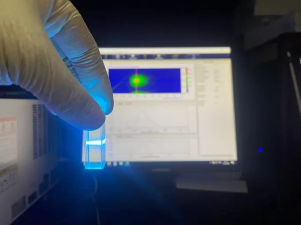 Лабораторное исследование: пробирка с жидкостью на фоне монитора.