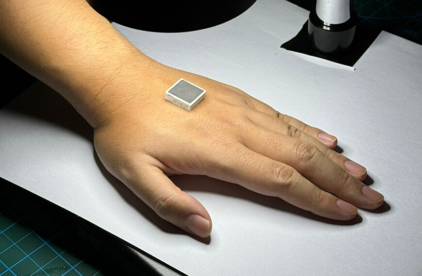 Рука с квадратным устройством на коже под светом на белой поверхности.