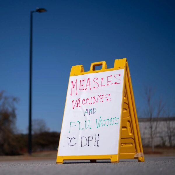 Табличка с информацией о вакцинах от кори и гриппа на улице.
