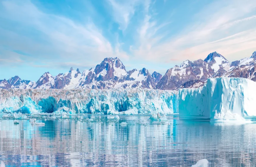 Горный пейзаж с айсбергами на фоне голубого неба, отражение в спокойной воде.