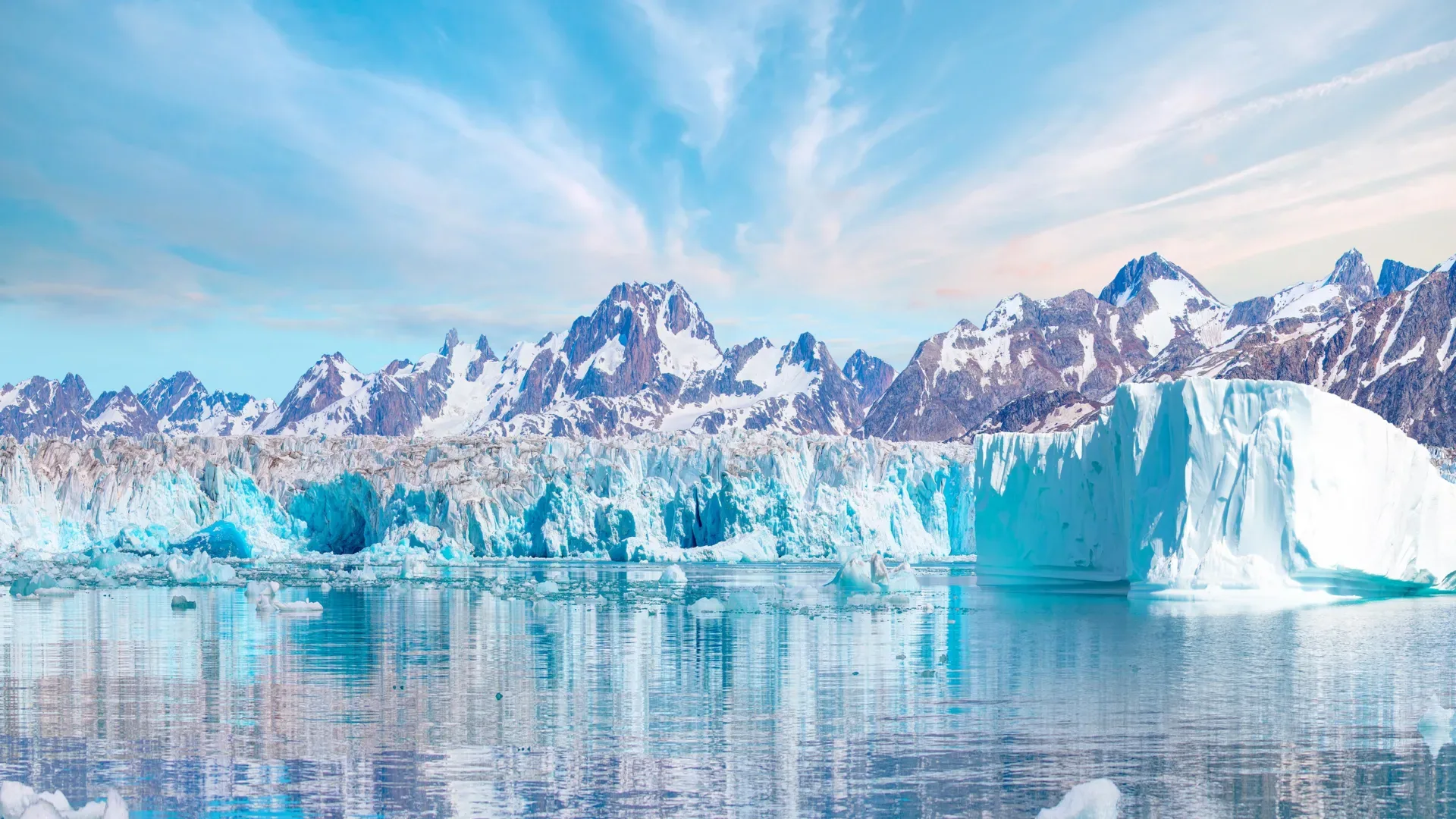 Горный пейзаж с айсбергами на фоне голубого неба, отражение в спокойной воде.