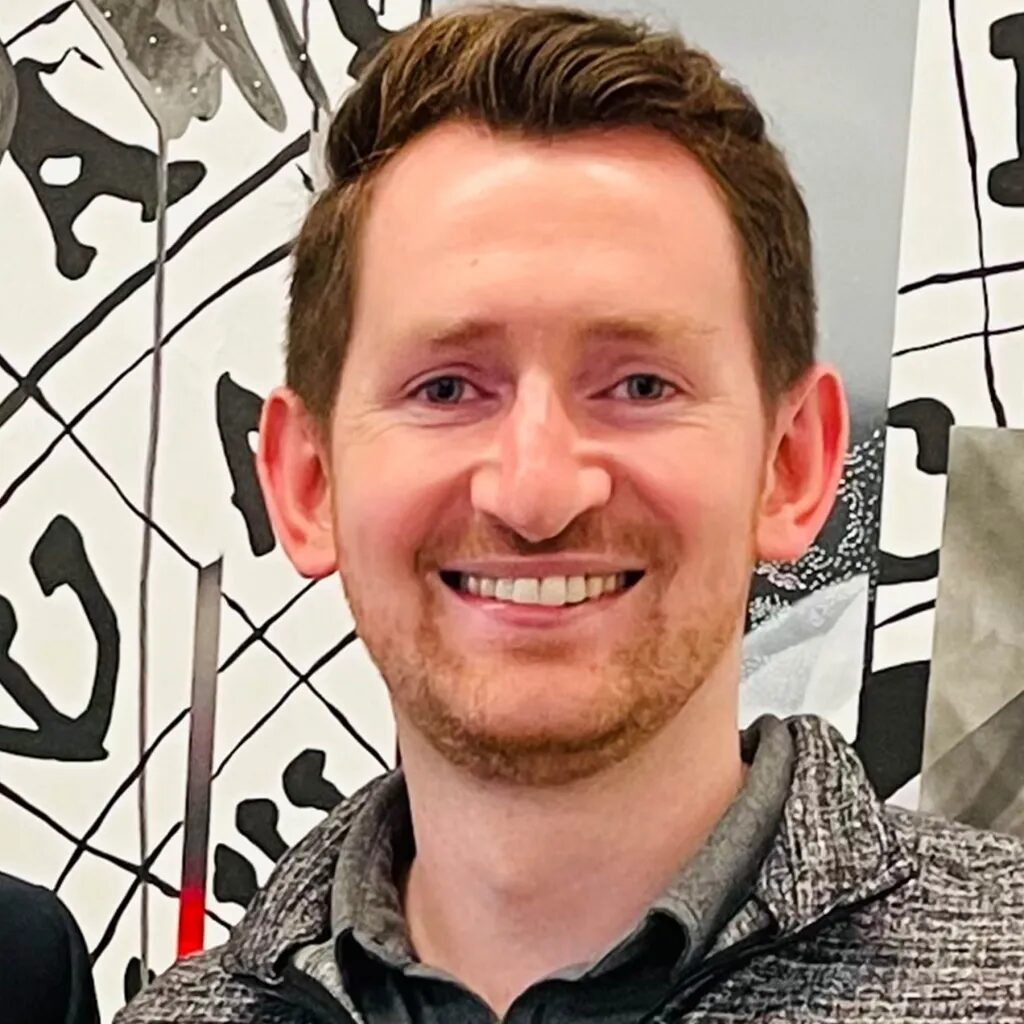 Изображение улыбающегося мужчины на фоне художественного рисунка.