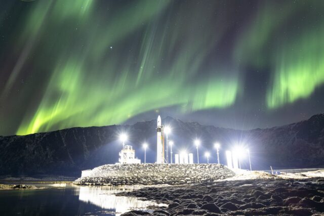 Северное сияние над космодромом на фоне гор и ночного неба.