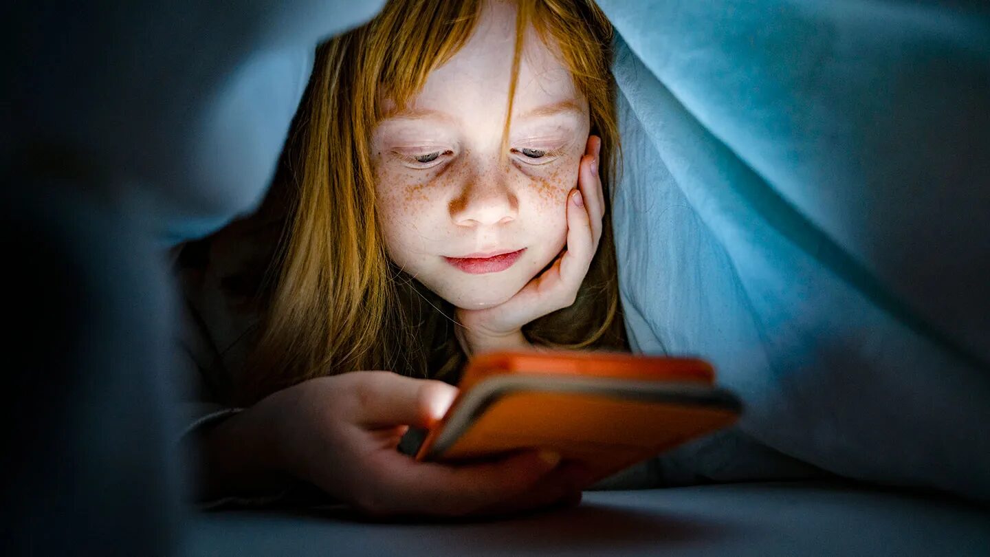 Исследование показало, что большое количество несовершеннолетних детей находятся в социальных сетях 1 бледный ребенок с веснушками прячется под одеялом, чтобы ночью воспользоваться мобильным телефоном