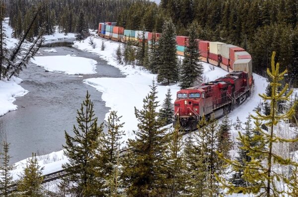 Грузовой поезд в зимнем лесу у реки, железная дорога и природа.