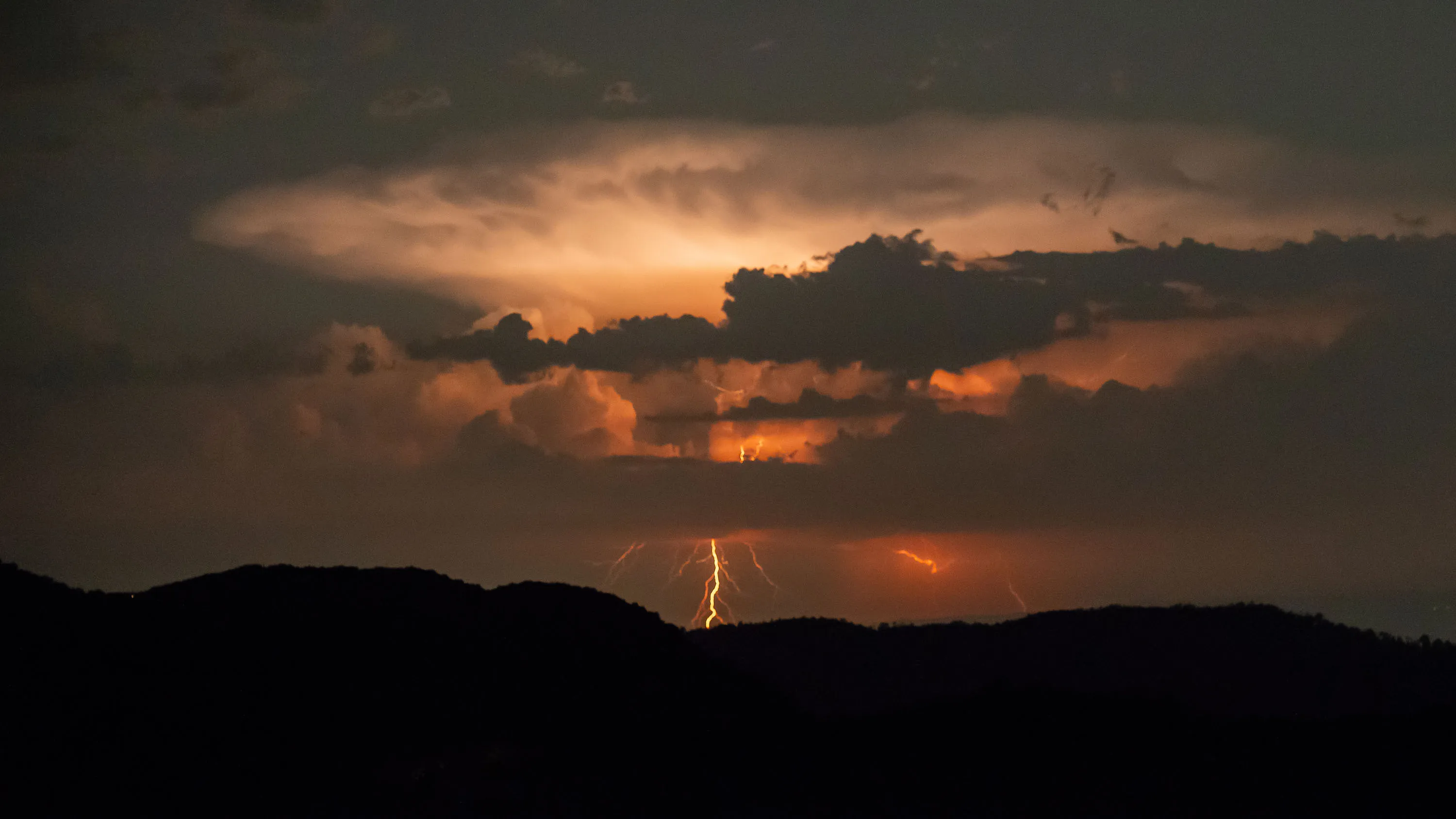 В горах сверкают молнии, небо окрашивается в зловещий красный цвет.