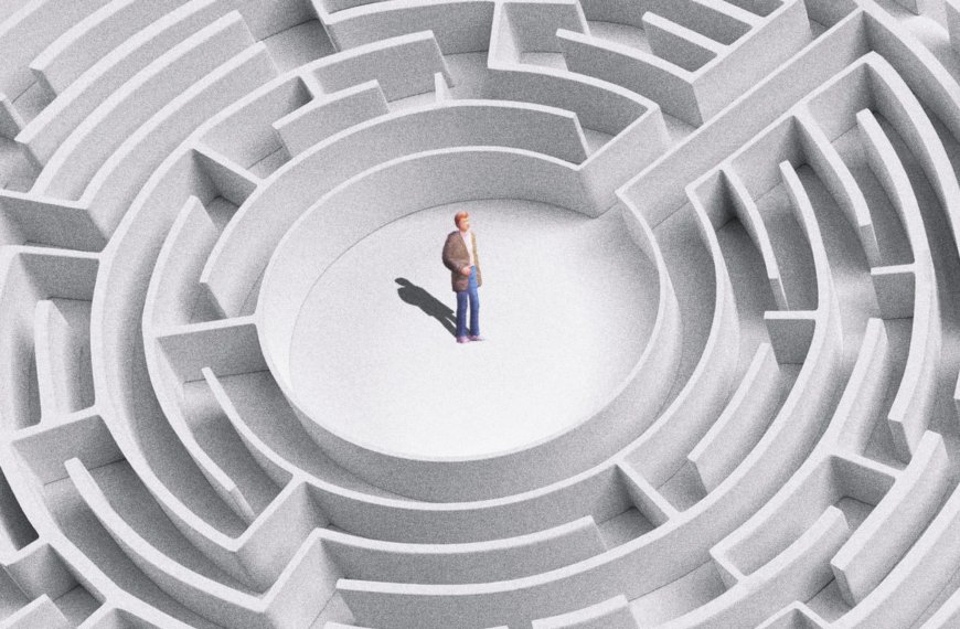 Человек в центре кругового лабиринта, серые стены, светлый фон.