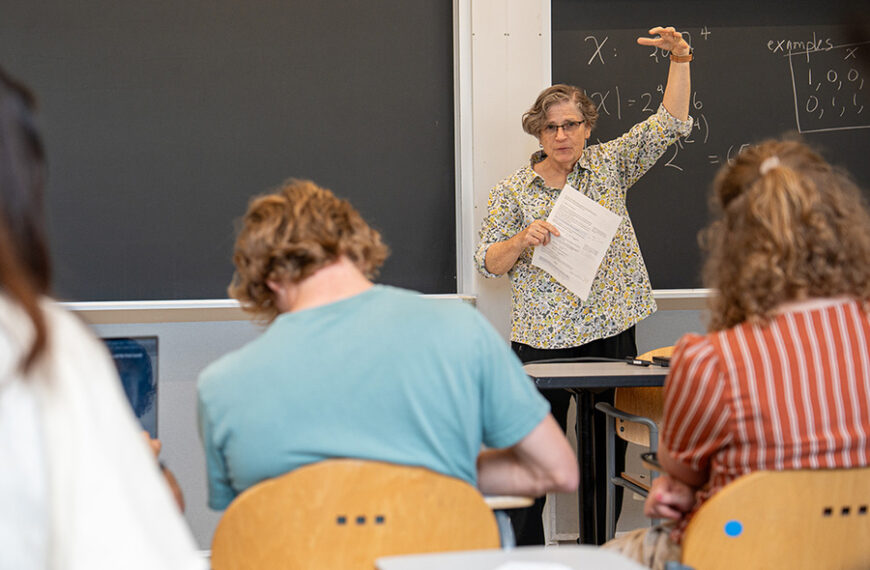 Учитель объясняет ученикам задачу на уроке математики у доски в классе.