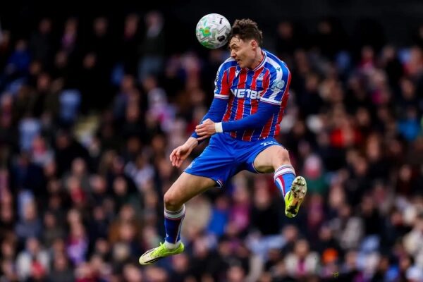 Футболист в полосатой форме выполняет удар головой по мячу на матче.