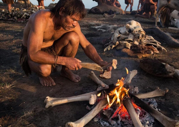 Пещерный человек у костра с костью и мясом, каменный век, археология.