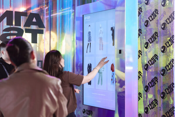 Женщина выбирает одежду на интерактивном экране в магазине.