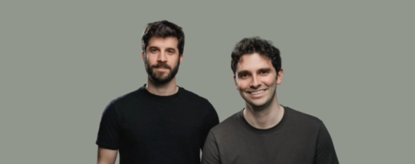 Два человека в тёмных футболках на сером фоне, лица размыты.