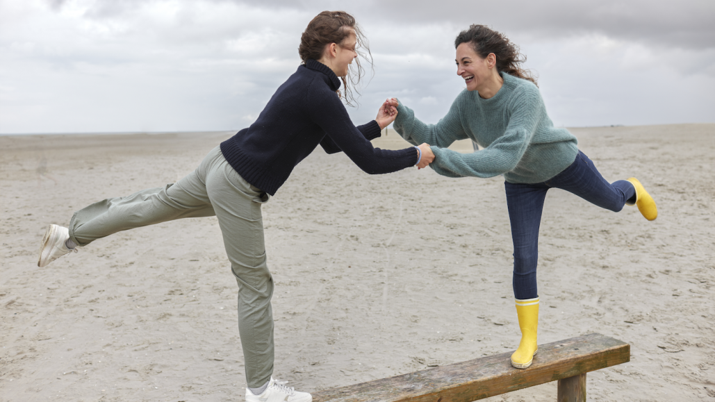 Ученые говорят: Равновесие 2 Две девушки в качестве упражнения балансируют на доске на пляже.
