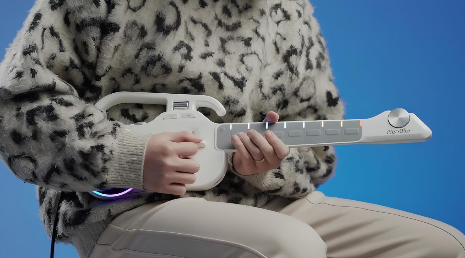 Человек играет на белой музыкальной гитаре на фоне синего цвета.