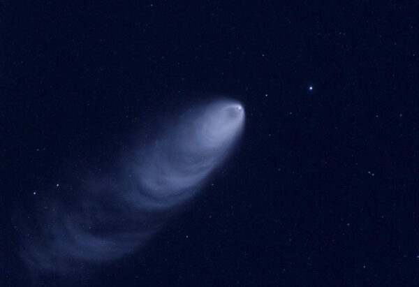 Космическое облако в форме хвоста на фоне звездного неба.